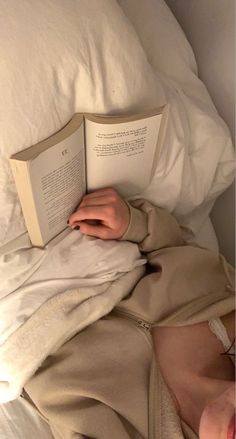 a person laying in bed reading a book