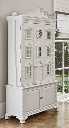 a large white doll house sitting on top of a wooden floor next to a window