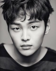 black and white photo of a young man with short hair looking at the camera while wearing a striped t - shirt