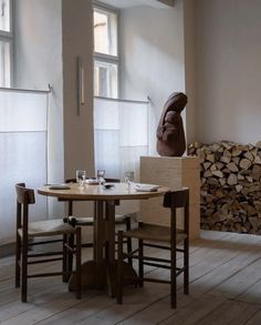 a table and chairs in a room with wood stacked on the floor next to each other