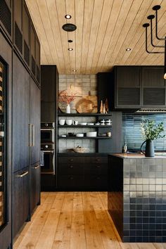 a kitchen with wooden floors and black cabinets