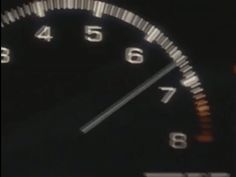 a close up of a speedometer in the dark with numbers on each side and an arrow pointing to the left