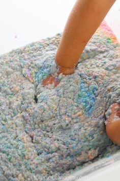 a child is playing with colored sand in a bowl