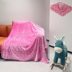 a couch covered with a pink blanket next to a stuffed animal