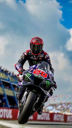 a man riding a motorcycle on top of a race track in front of a crowd