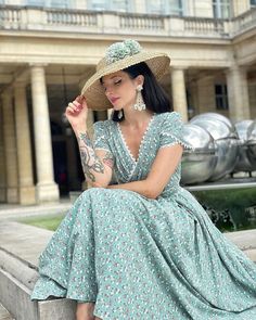 a woman in a dress and hat sitting on a ledge