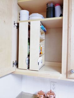 an open cabinet in a kitchen filled with pots and pans