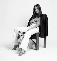 a black and white photo of a woman sitting on a chair with her dog