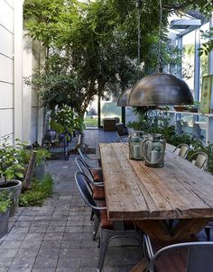 a wooden table sitting on top of a patio next to potted plants and trees