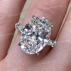 a close up view of a diamond ring on someone's finger, with the center stone