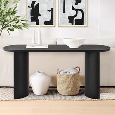 a black table with two white vases sitting on top of it next to a plant