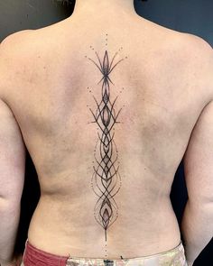 the back of a woman's body with an intricate tattoo on her lower back