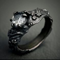 a close up of a ring on a black surface with flowers and leaves around it