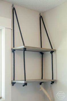 an empty shelf with rope hanging from it's sides in the corner of a room