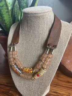 a necklace on a mannequin neck with beads and leather cord hanging from it