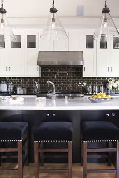 a kitchen with white cabinets and black bar stools