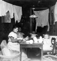 an old black and white photo of two women sitting at a table with a baby