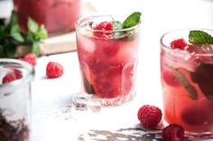 two glasses filled with raspberry lemonade and mint spritz on top of a table