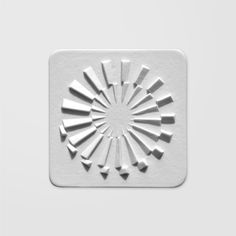 a white square button with an abstract design on the front and center, which is shaped like a sunburst