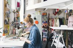 a woman working on a sewing machine in a room with lots of crafting supplies