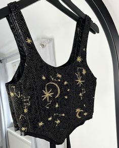 This soft, black, velvet, boned corset features gold star and moon glittering details, embroidered onto tulle, that shimmer under the moonlight and dance under a disco ball. This corset is a must have for your NYE party. Corsets are lined with black satin and have a ribbon tie up back allowing you to adjust it to your personal style and fit. - Hand wash only  if you have any questions please don't hesitate to message us!  Check out our website for lots more!! https://eccentriclothing.bigcartel.c Diy Rhinestone Corset, Black Corset For Party Season, Fitted Black Corset For Dance, Sequined Corset For Party Season, Embellished Black Corset For Night Out, Black Sequined Corset For Night Out, Black Embellished Corset For Night Out, Black Embellished Sleeveless Corset, Black Sleeveless Embellished Corset