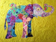 an elephant made out of fabric on a yellow quilted wallhanger with flowers