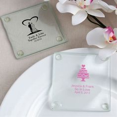 a glass plate with a wedding cake on it next to a pink flower and some white orchids