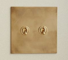 two golden lights are on the wall in front of an electrical outlet with one light switch