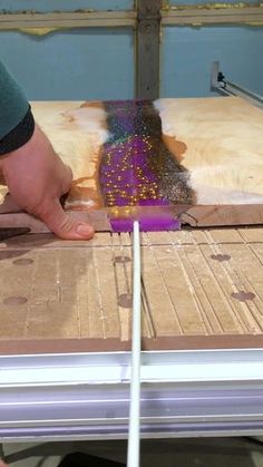 a person using a brush to paint the wood with purple and gold flecks