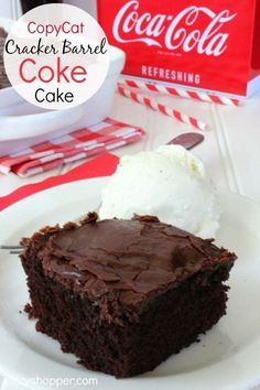 a piece of cake on a plate with ice cream and coca cola in the background