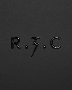 the letters r and c are made out of black paper with metallic lettering on it