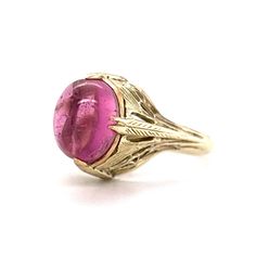 This one of a kind Art Deco ring features a light pink tourmaline in 14 karat yellow gold. The tourmaline reflects a romantic, taffy pink hue. Cabochon cut and smoothly polished. The antique shoulders of the band feature geometric engravings. Decorative and fashionable. Finished in 14 karat yellow gold. This statement cocktail ring is a treasure from the Art Deco era. Pink Tourmaline Ring, Gold Art Deco, Pink Jewelry, Tourmaline Ring, Shop Engagement Rings, Art Deco Ring, Jewelry Inspo, Pink Tourmaline, Shop Necklaces