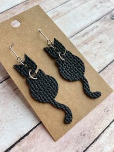 The cutest cat earrings! Made with stainless steel earring findings and faux leather (single-sided).  Each pair of earrings will be slightly different because of the variability in the faux leather pattern.  2.625 inches long by .625 inches wide. Free shipping on orders $35 and over! Warning: Choking Hazard. Small Parts. Keep out of reach of children under 5 years old. Faux Leather Knot Earrings Diy, Homemade Leather Earrings, Faux Leather Earring, Leather Cricut Earrings, Cricut Faux Leather Earrings, Faux Earring Ideas, Faux Leather Halloween Earrings, Faux Leather Jewelry, Halloween Faux Leather Earrings