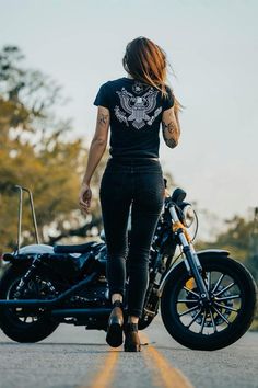 a woman walking down the road next to a motorcycle