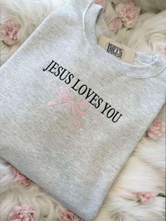 Welcome to our Etsy shop and check out our website www.ShopRusticHills.com. Wrap yourself in both comfort and inspiration with our "Jesus Loves You" embroidered sweatshirt, featuring a delicate pink bow detail. Crafted with care, this cozy sweatshirt is perfect for those seeking to share their faith in style. Whether it's for yourself or as a thoughtful gift, this sweatshirt is a beautiful reminder of love and grace. Available in various sizes and colors to match your unique look! Shipping Policy: We are not responsible for lost nor stolen packages once handed off to UPS or USPS, but we will help. They will have to get up with the carrier if a problem comes up. Valentine’s Day Embroidery, Embroidery Sweatshirt Ideas, Pearl Stitch, Jesus Sweater, Christian Sweaters, Christian Embroidery, Christian Clothing Brand, Jesus Clothes, Christian Valentines