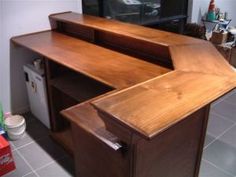 a wooden desk with drawers and a television in the backgroung area behind it