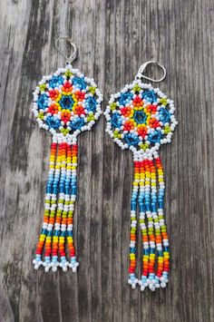 two colorful beaded earrings hanging on a wooden surface