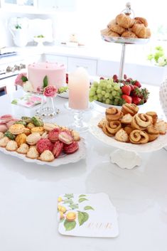 a table topped with plates filled with pastries and desserts next to a candle