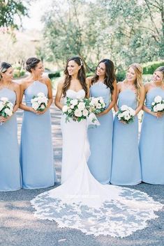 a bride and her bridesmaids standing together in blue dresses with white bouquets