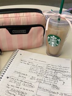 a cup of coffee next to a notebook and a starbucks bag