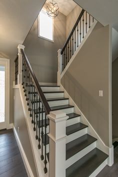 a staircase with black railing and white handrails in an empty home's entryway