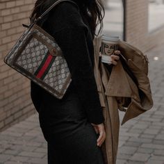 a woman is walking down the street with her purse and coffee cup in her hand