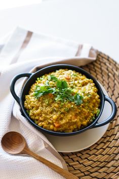 a bowl filled with food sitting on top of a table next to a wooden spoon