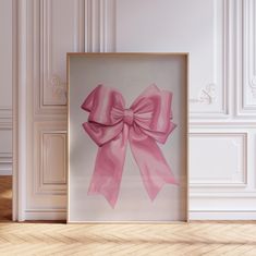 a pink bow is hanging on the wall next to a framed photograph in an empty room