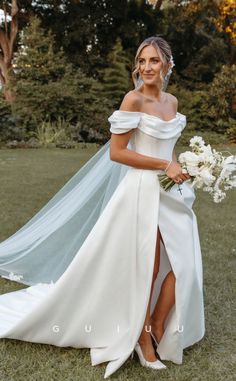 a woman in a white wedding dress posing for the camera with her bouquet and veil