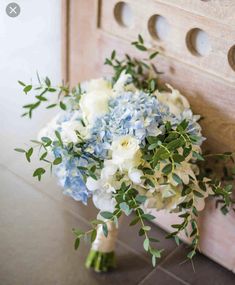 a bridal bouquet sitting on top of a counter next to a wooden door with holes in it