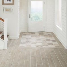 a hallway with white walls and wood flooring next to a door that leads to another room