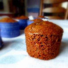 a muffin sitting on top of a table next to some blue cups and spoons