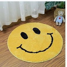 a smiley face rug on the floor next to a teddy bear and potted plant