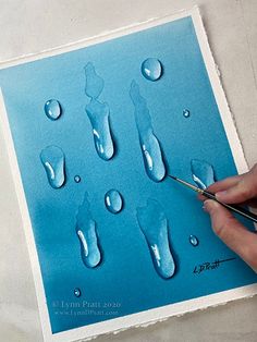 someone is painting water drops on a piece of paper